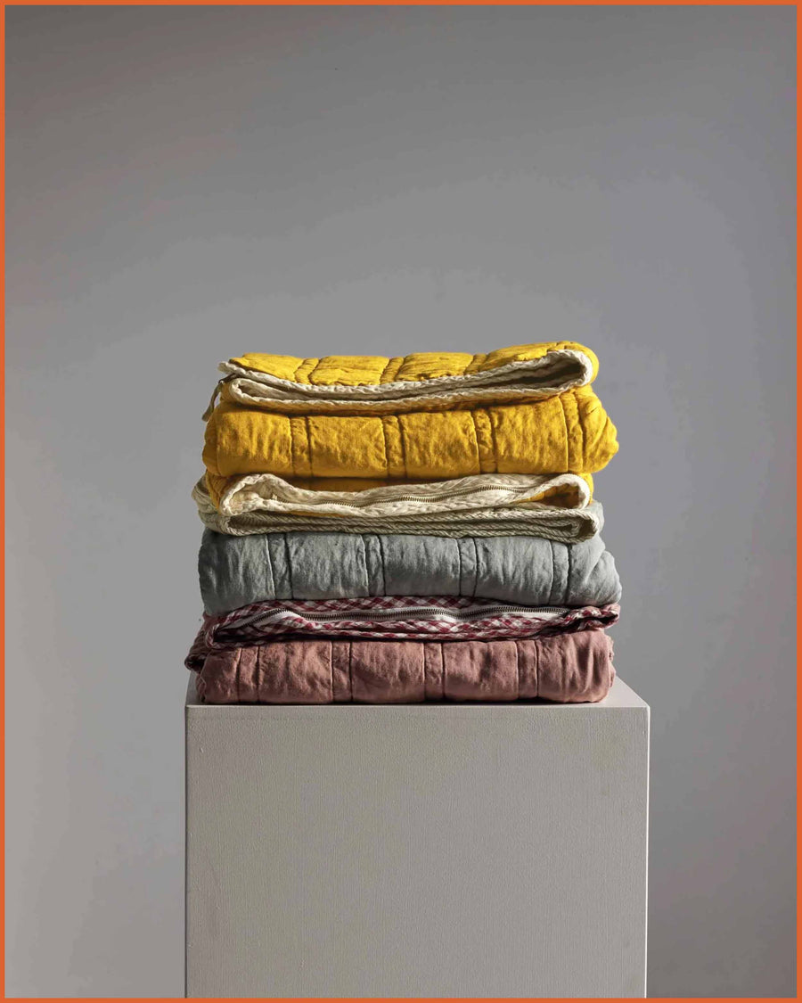 Stack of French linen sleeping bags in Lemon and Butter Yellow