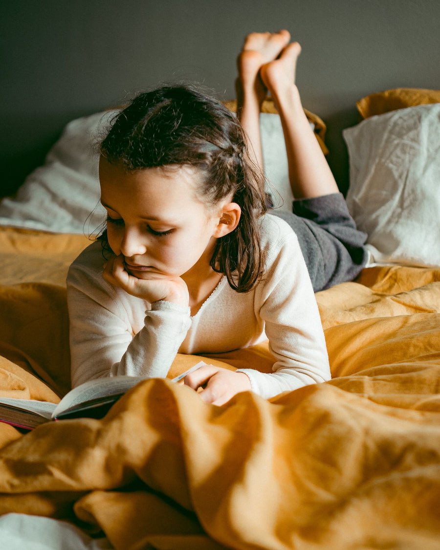 Child reading on Marigold French flax linen bedding